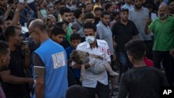 গাজা ভুখন্ডের খান ইউনিসে বিমান হামলার পর একজন শিশুকে নিয়ে যাওয়া হচ্ছে , অক্টোবর ২১,২০২৩ 