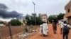 Smoke rises above buildings as people flee with some belongings, in Khartoum, Sudan, June 10, 2023. 