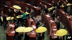 Pro-democracy legislators hold up yellow umbrellas and banners stating "I want real universal suffrage" and "Leung Chun-ying Step down" as they walk out of the Legislative Council during Hong Kong Chief Executive Leung Chun-ying's annual policy address in