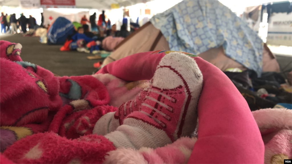 Una bebé espera en su cochecito con su familia rodeándola mientras esperan en la frontera después de días de llegar con la esperanza de cruzar a Ecuador. Ipiales, Colombia, 11 de septiembre de 2019. Foto: Celia Mendoza - VOA.