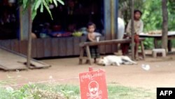 Trẻ em ngồi gần một bãi mìn bên ngoài căn nhà ở tỉnh Battambang, tây bắc Campuchia
