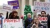 FILE - Laura Hayes (with microphone), of Fort Wayne, Indiana tells fellow protestors how the Affordable Care Act helped her with health costs, during a protest in front of the Supreme Court in Washington.