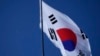A South Korean national flag flutters in the wind at the Unification Observation Post as North Korean balloons, left, fly in Paju, South Korea, near the border with North Korea, Oct. 4, 2024.