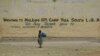 Un niño pasa frente a un cartel que da la bienvenida a refugiados que huyen de la milicia extremista Boko Haram, en Nigeria.