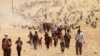 FILE - Displaced minority Yazidis, fleeing violence from forces loyal to the Islamic State in Sinjar town, walk toward the Syrian border, on the outskirts of Sinjar mountain, near Elierbeh of Al-Hasakah Governorate, Aug. 10, 2014. 