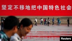 资料照：北京的行人走过天安门广场的一幅巨幅标语。（2012年6月3日）