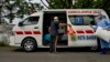 Seorang pasien virus corona (kiri) berbincang dengan petugas medis sebelum naik ke ambulans untuk pulang ke rumahnya dari RSUD Zainoel Abidin di Banda Aceh, 13 April 2020. (Foto: AFP)