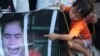 A child of Boeung Kak lake community's land activists points a poster of detained Tep Vanny in front of the appeals court in Phnom Penh, Cambodia, Tuesday, Aug. 8, 2017. (AP Photo/Heng Sinith)
