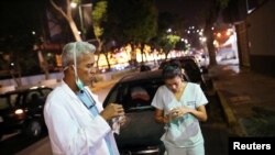 Deux médecins prenant une collation pendant dans une station-service lors de la quarantaine nationale en raison de l'épidémie de coronavirus, Caracas, Venezuela, 7 avril 2020. (Reuters/Manaure Quintero)